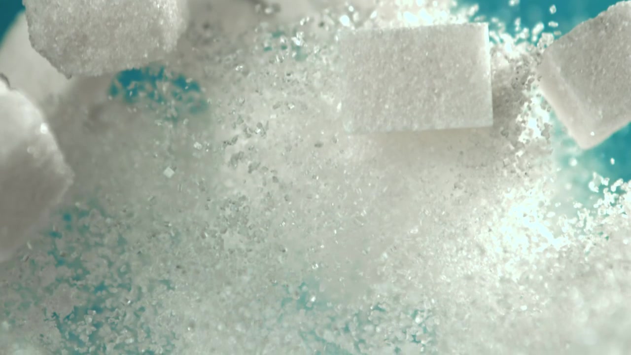 Cámara lenta de terrones de azúcar y azúcar granulada cayendo