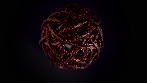primer plano estático de una bola de navidad giratoria en rojo oscuro con brillo