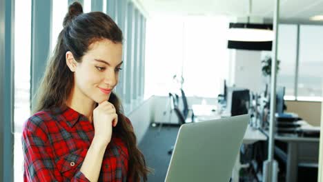 Smiling-female-executive-using-laptop