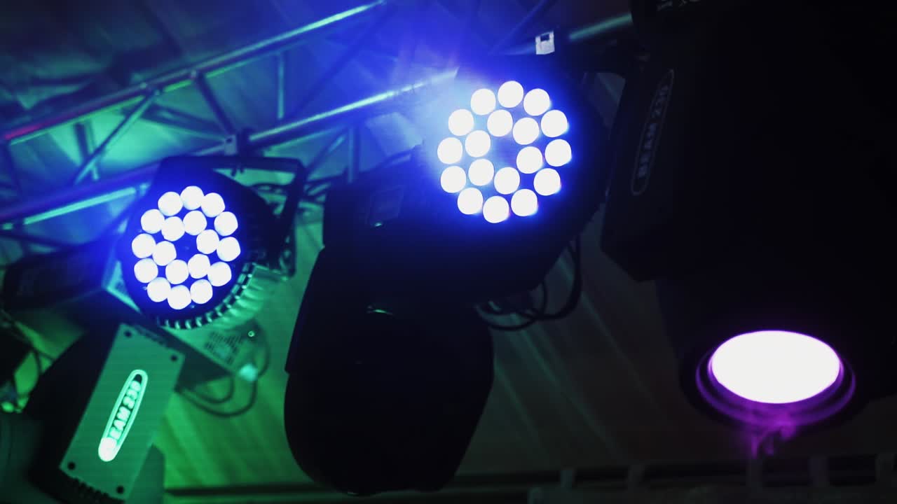 Musical farm in the night club. Colorful spotlights hang under hall ceiling and rotating with bright lights at darkness.