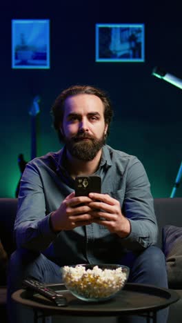 vertical video man relaxing on couch at home texting friends on smartphone