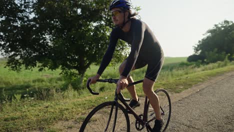 Sportsman-rides-bicycle-along-the-asphalt-road-alone