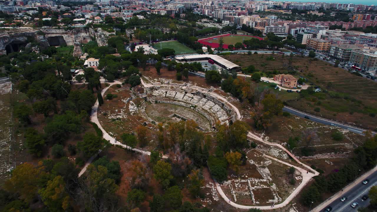 Siracusa Roman ruins, pathways and historic amphitheater in archaeological park. Aerial drone Italy.