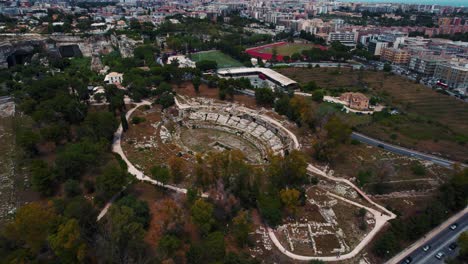 siracusa roman ruins, pathways and historic amphitheater in archaeological park. aerial drone italy.