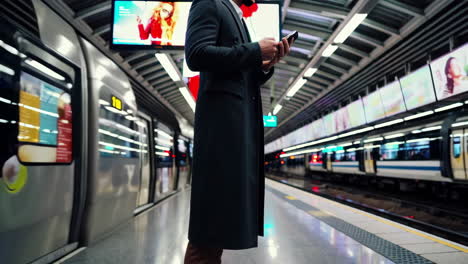 man using phone on a subway platform