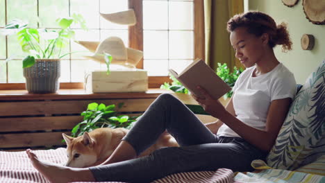 young woman reading a book in her bedroom with dog