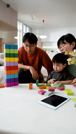 family playing with wooden blocks and a tablet