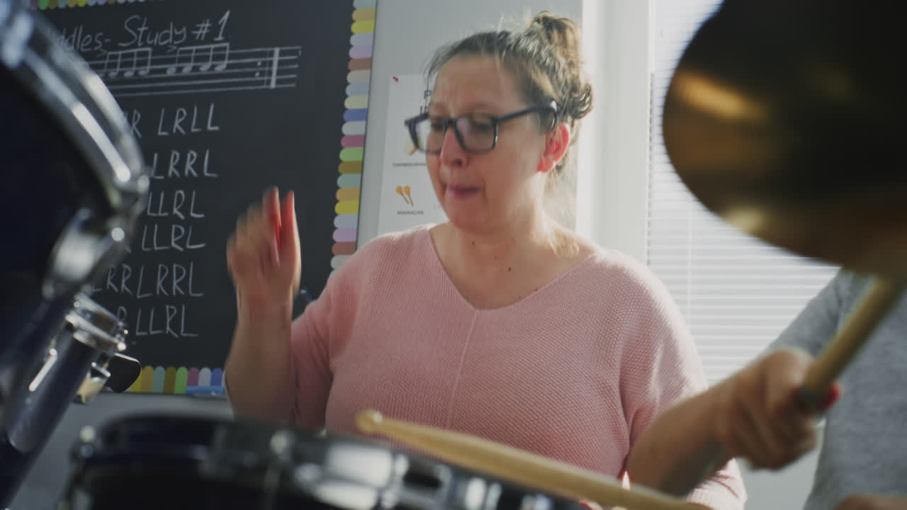 Female Teacher Educating Talented Boy to Play Drum Set During Percussion Lesson