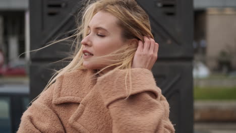 young woman holding hair from wind.