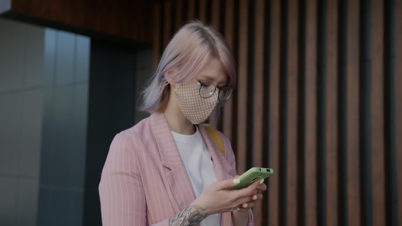 Woman using phone outdoors wearing face mask