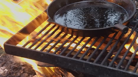 cast iron pan with removable handle is seasoned with oil on open fire