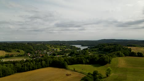 Absteigende-Luftaufnahme-Eines-Kleinen-Polnischen-Dorfes-Und-Eines-Schönen-Ländlichen-Ackerlandes-Mit-Unterschiedlichem-Anbau-Auf-Dem-Land-In-Polen