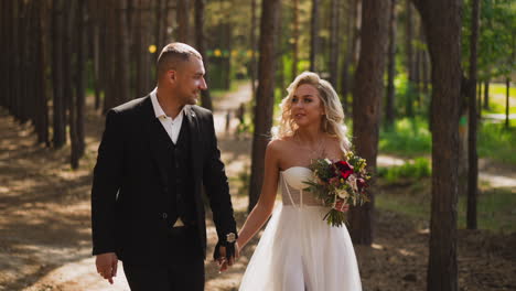 newlywed couple walks joining hands along sunny green park