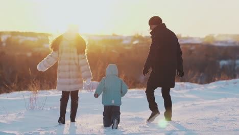 parents and son in jacket jump against orange sunset