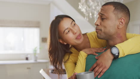 feliz pareja biracial con café hablando y abrazándose