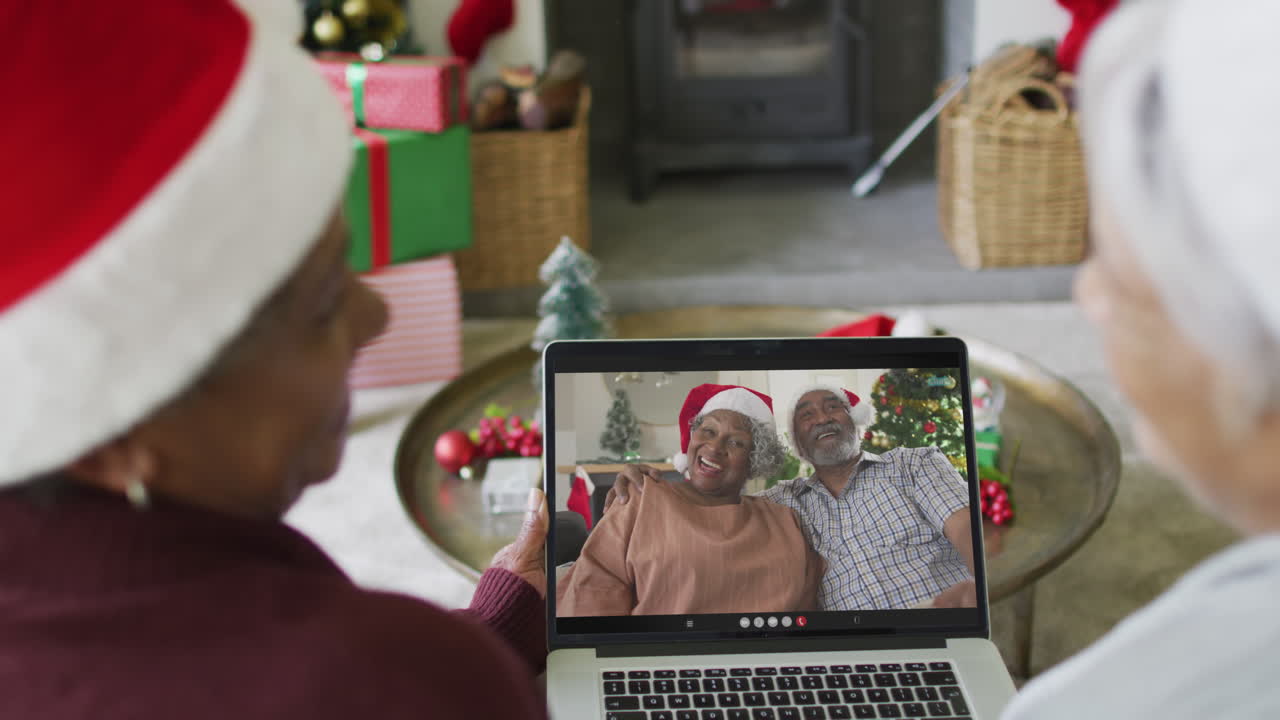 sonriendo diversas amigas mayores usando una computadora portátil para una videollamada de navidad con una pareja en la pantalla
