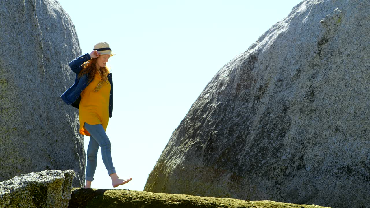 mujer caminando sobre una roca en la playa 4k