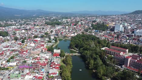 4k forward aerial view drone shot of the walk of the lake bridge surrounded by nature and residential houses of xalapa, veracruz at daytime