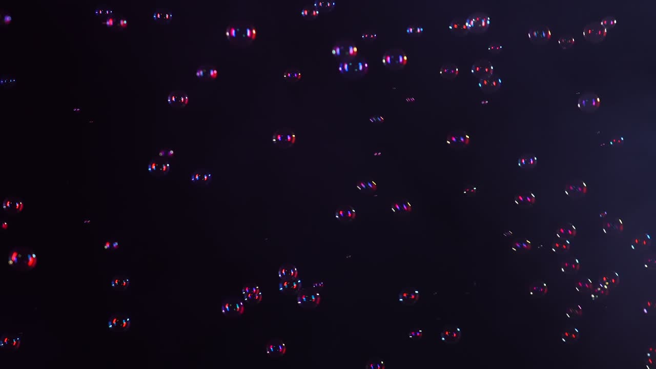 아름다운 비누 거품은 은 네온 빛에 검은 바탕에 연기가있는 스튜디오에서 날아갑니다. 느린 움직임.