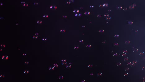beautiful soap bubbles fly in a smoky studio on a black background in red neon light. slow motion. close up