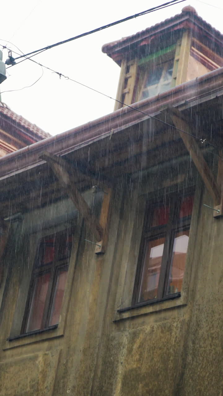 rainfall on the background of urban architecture. Drops of rain are falling on the background of a old building. Vertical video