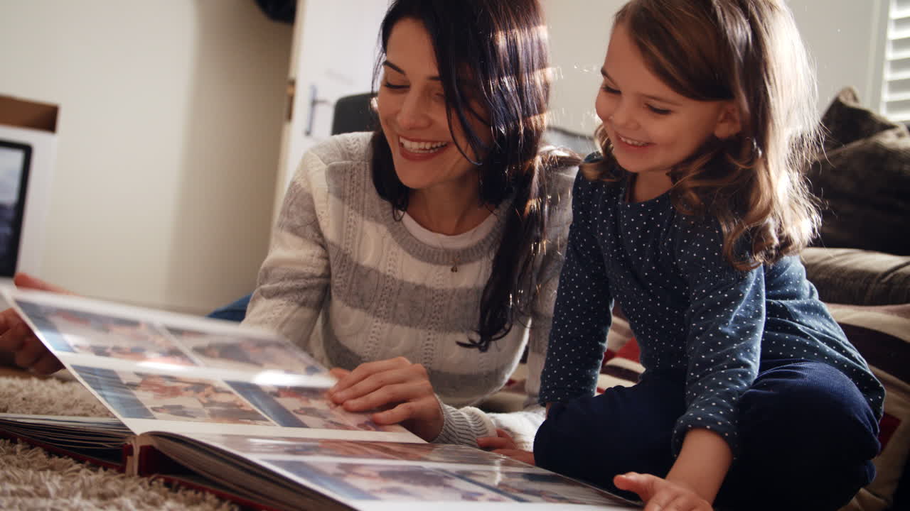madre e hija en casa mirando a través del álbum de fotos