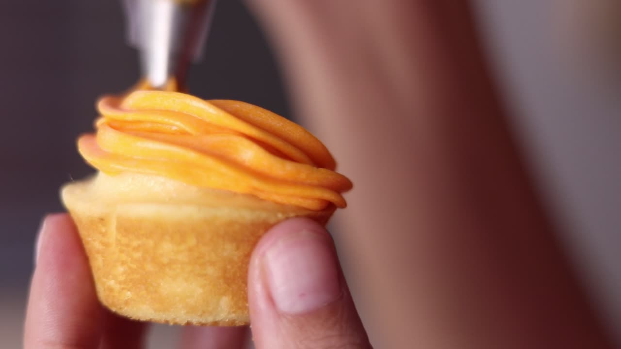 cerca de un pequeño pastel de taza que está cubierto de glaseado de naranja