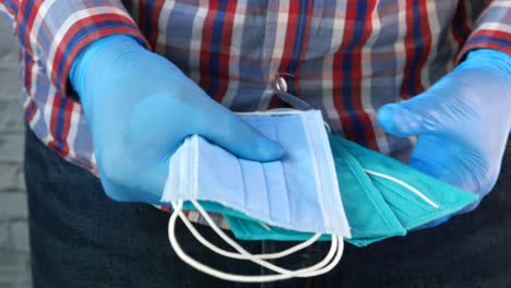 person holding face masks in blue gloves