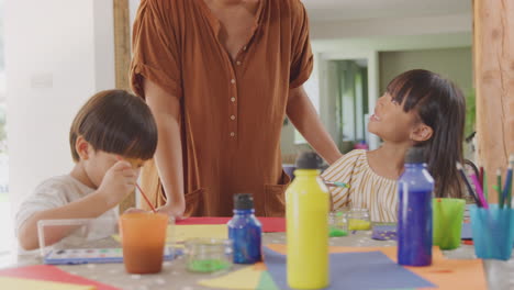 asian mother having fun with children doing craft on table at home