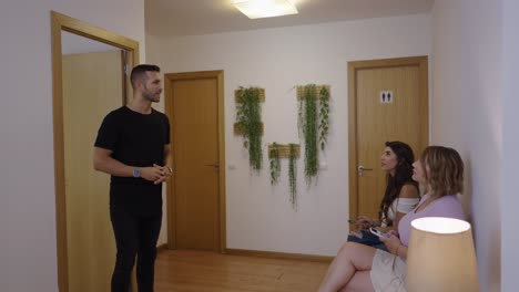 man enters and interacts with women in a waiting room