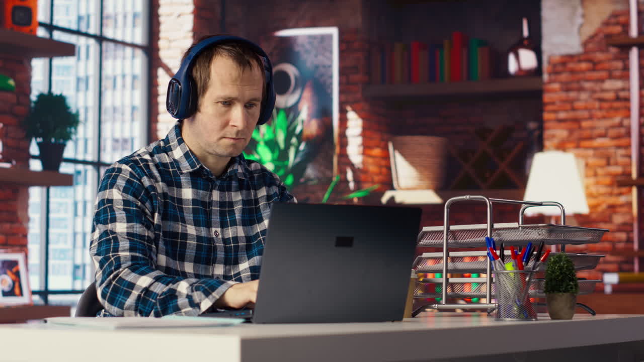 Colaborador ouvindo música, analisando dados no notebook na mesa
