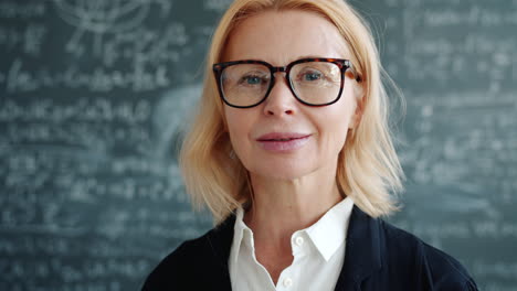 portrait of a smiling teacher in front of a chalkboard