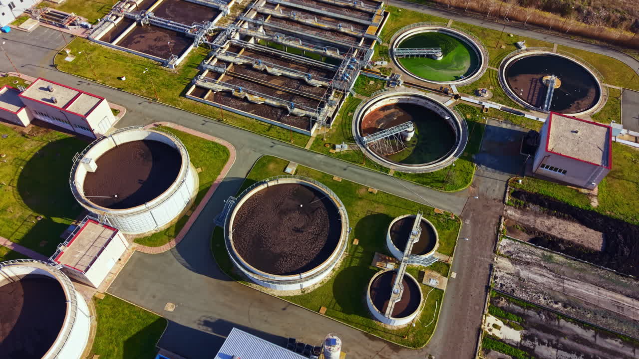 Wastewater treatment plant with multiple tanks and processing areas viewed from above in daylight
