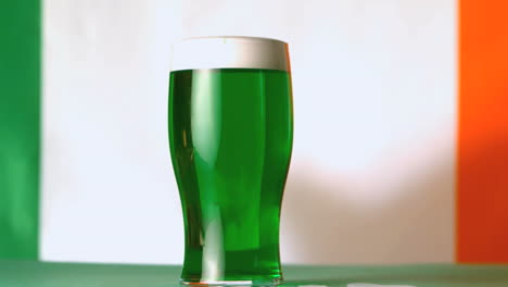 gran trébol verde cayendo al lado de una pinta de cerveza verde