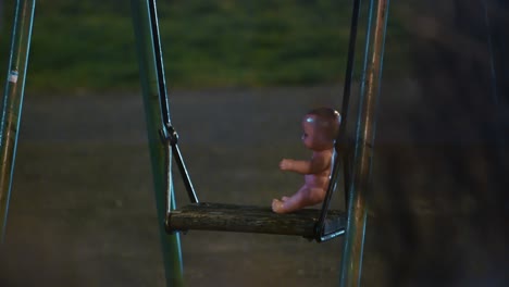 plastic baby doll left alone on swing in zagreb playground at night