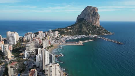 Skyline-Der-Stadt-Calpe,-Promenade-Und-Felsen-Penon-De-Ifach-An-Der-Costa-Blanca,-Spanien---Luftaufnahme-4k