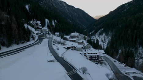 Vuelo-Aéreo-Sobre-Un-Camino-Sinuoso-Que-Pasa-Por-Hoteles-Resort-En-El-Paso-Stelvio-Por-La-Noche