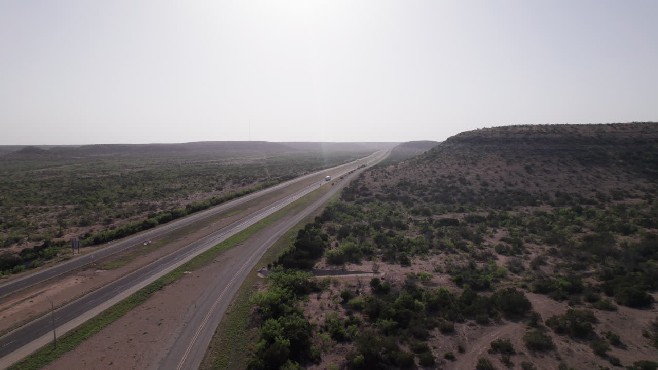 aerial view of distant 18 wheelers transporting containers across the west Texas desert on Highway I-10