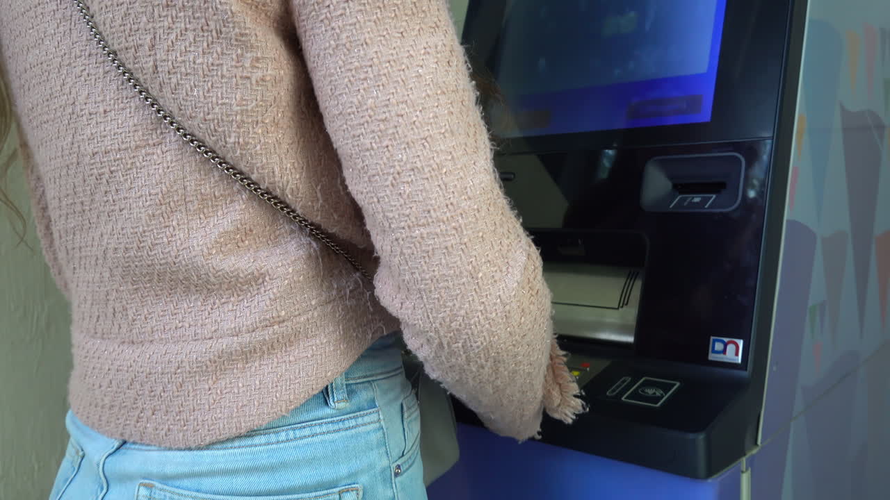 Woman introducing a card and touching the screen of an ATM