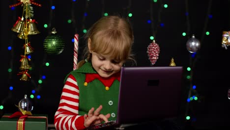 Niña-Vestida-De-Elfo-Navideño-Haciendo-Compras-En-Línea-Usando-Una-Computadora-Portátil,-Navegando-En-Las-Redes-Sociales