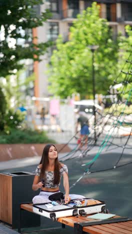 teenage girl packing suitcase in a park