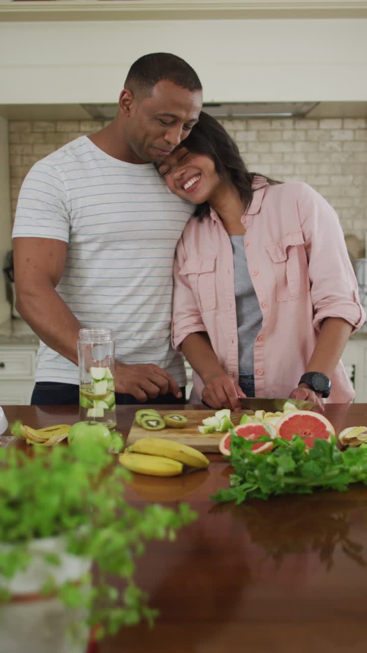 video vertical de una pareja feliz y diversa preparando comida juntos en la cocina