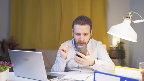 Man-working-from-home-enjoys-mobile-apps-on-phone.