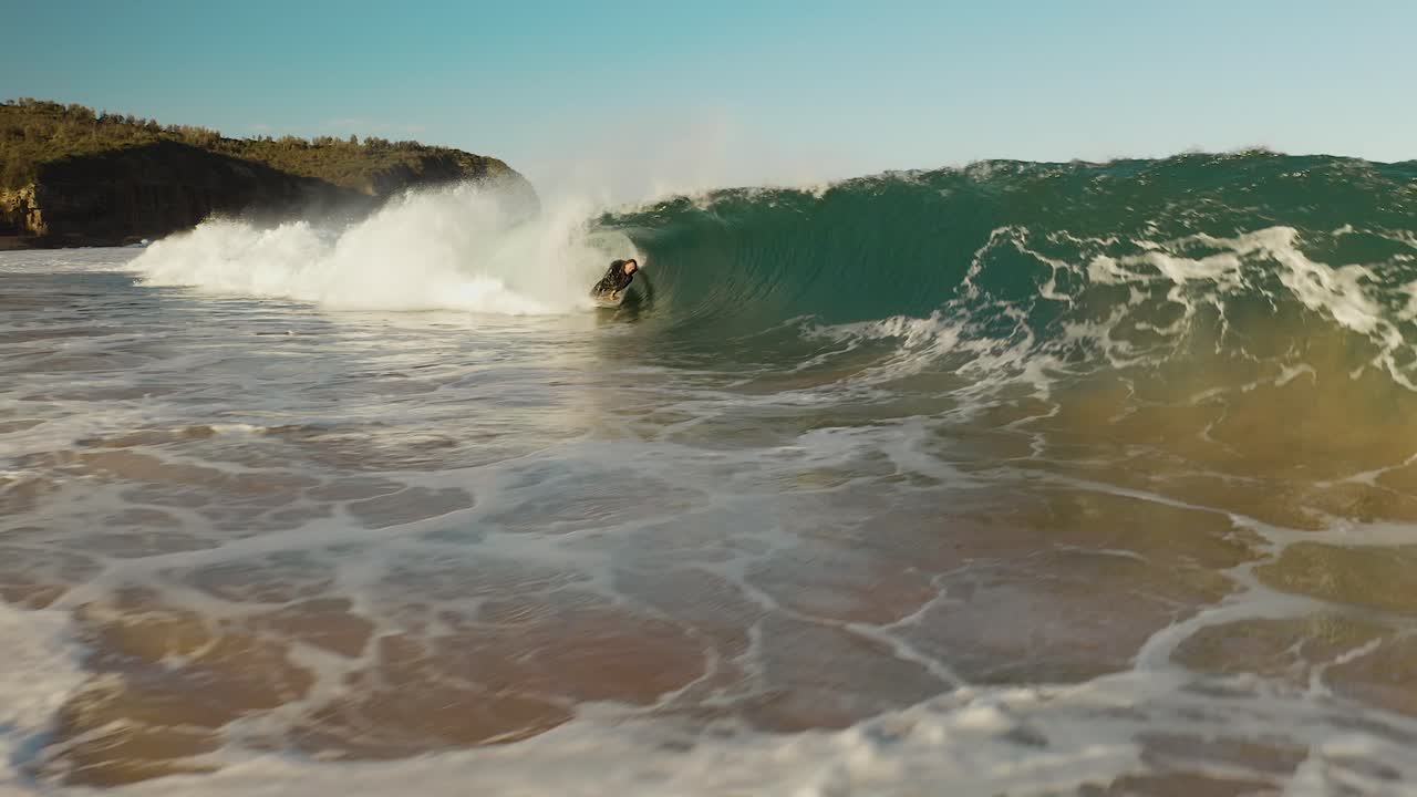 Surfer rides into big close out wave, surfing in Sydney, slow motion drone aerial shot