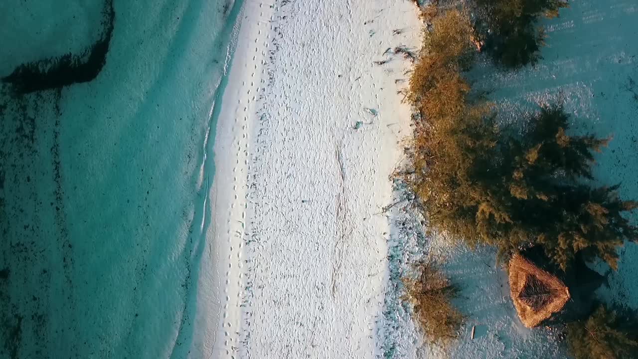 Soft bird's eye view top view slowly forwards drone shot at dream beach with a hut