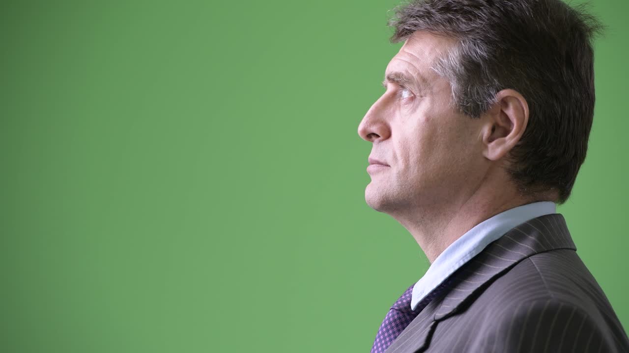 Mature handsome businessman against green background