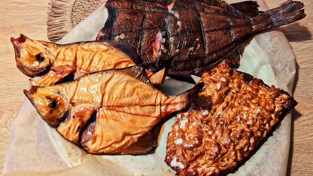 Assorted smoked fish meats resting on wooden board, rustic barbecue style food ready to eat