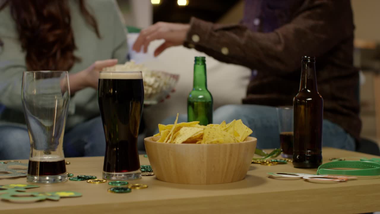 cerca de los amigos en casa celebrando en la fiesta del día de san patricio bebiendo alcohol y comiendo palomitas de maíz 3