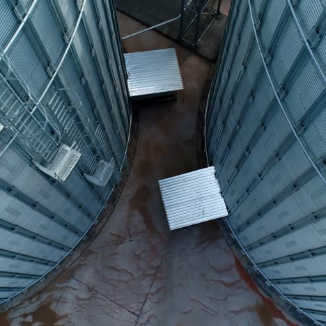 modern agricultural containers. metal grain elevators. large storage tanks for storing grain. metallic bins. aerial view. motion camera top down.
