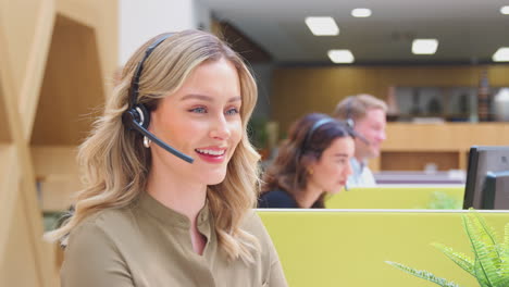 Businesswoman-Wearing-Phone-Headset-Talking-To-Caller-In-Customer-Services-Centre